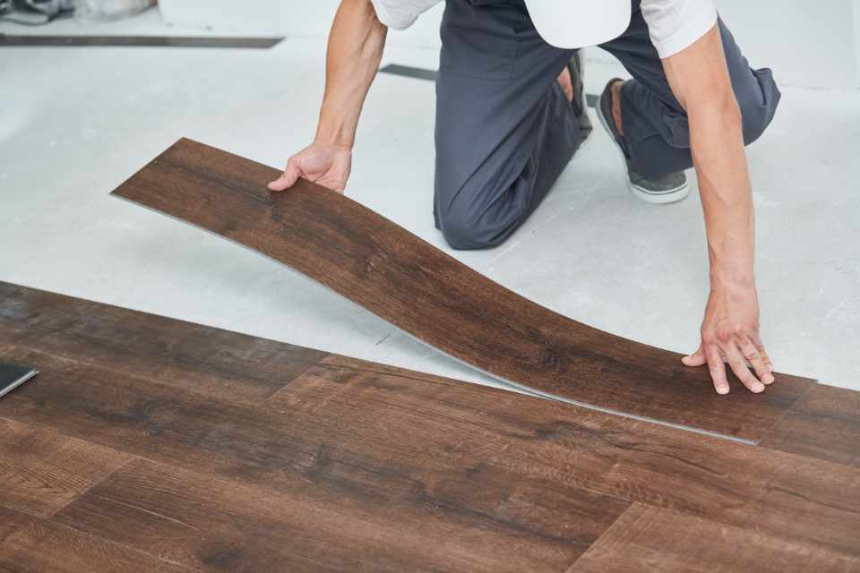 installing dark wood-look luxury vinyl planks in new home